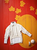 Short white knitted sweater with shirt on patterned background