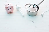 Piggy bank, saucepan and light stick on white background