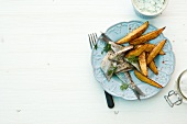 Young herring with chilli powder, potato wedges and spring on plate