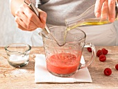 Close-up of hand stirring raspberry vinaigrette in jar