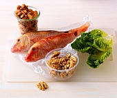 Fish, lettuce, almonds and walnuts on white background
