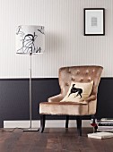 Upholstered armchair and standard lamp against wall with black dado below striped wallpaper