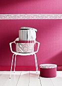 Hutschachteln auf weißem Stuhl, vor pinkfarbener Wand