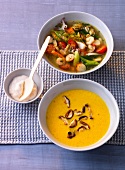 Yellow bell pepper soup and seafood soup in bowls