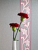 Close-up of flower vase against floral patterned wallpaper