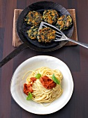 Spaghetti with red pesto and spinach taler in serving dish