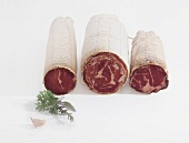 Three different varieties of coppa on white background