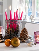 Lit candles in candle holder with larch cones on plate for Christmas