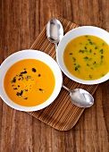 Bowl of pumpkin and carrot soup and cream of potato soup on tray 