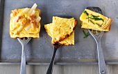Asparagus tart, cheese omelettes and Spanish omelettes on three spatulas