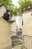 Man sitting in front of James Douglas Morrison grave in Pere Lachaise, Paris