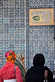 Woman standing in front of wall of faience ornaments in Topkapi Palace, Istanbul