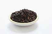 Bowl of black pepper on white background