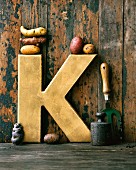 An arrangement featuring a golden letter K and various types of potatoes