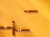 Close-up of four cigars on yellow background