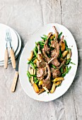 Lamb chops on a bed of green beans served with potato wedges