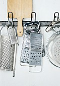 Various graters and vegetable slicers hanging on a wall
