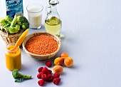 Oil, milk, raspberries, lentils, broccoli and peaches on white background, copy space