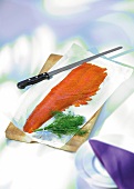 Smoked salmon with dill and knife on wooden board