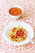 A bowl of baby food and a plate of spaghetti with vegetable bolognese