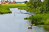 Men canoeing in lake while passing through Ukta in Ruciane-Nida, Warmia-Masuria, Poland