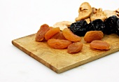 Mixed dry fruits on wooden platter on white background