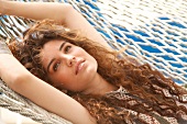 Woman with long brown hair relaxes in a hammock