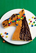 Horse head shaped gluten free cake for kids birthday with colourful candies on plate