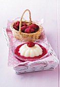 Custard with raspberry sauce in glass bowl and basket of raspberries