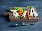 Whole and chopped vegetables on wooden board