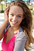 Portrait of beautiful blonde woman wearing pink and gray top, smiling