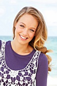 Portrait of happy blonde woman wearing white mesh top over purple t-shirt, smiling