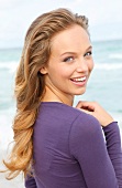 Portrait of beautiful blonde woman wearing purple top, smiling