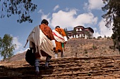 Monks climbing up steps of Ta Dzong national museum in Paro, Bhutan