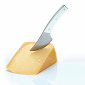 Close-up of parmesan cheese with cheese knife on white background