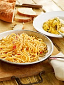 Close-up of spaghetti with garlic and hot peppers in pan and plate