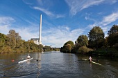 Nina Wengert kayaking in river against power station, Saarland, Germany