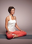 Beckenboden-Yoga, Frau sitzt, Hände auf den Oberschenkeln