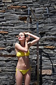 Frau im gelben Bikini duscht im Freien
