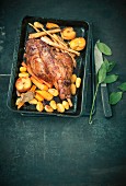 Braised leg of lamb with carrots, apples and potatoes in a roasting tin