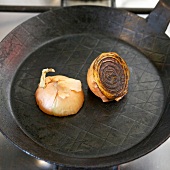 Close-up of halved onion being fried in pan, step 1