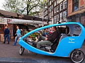 Man in pedicab near flower market on the Singel, Amsterdam, Netherlands