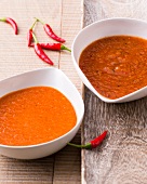 Two bowls of apricot sauce and hot and sour chilli sauce