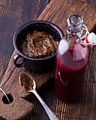 Bottle of cherry ketchup and barbeque sauce pepper in cup on wooden board