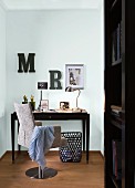 Photos and miniature Eiffel Tower on desk with swivel chair and decorative letters on wall