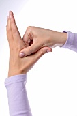 Right hand pressing left hand between thumb and index finger, performing acupressure