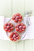 Four strawberry tartlets with icing sugar on plate 