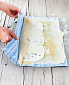 Strudel and quark mass being rolled with cloth for preparing cheese cake, step 2