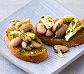 Crostini with beans and artichokes on plates