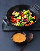 Stir fried vegetables in casserole with peanut sauce in bowl